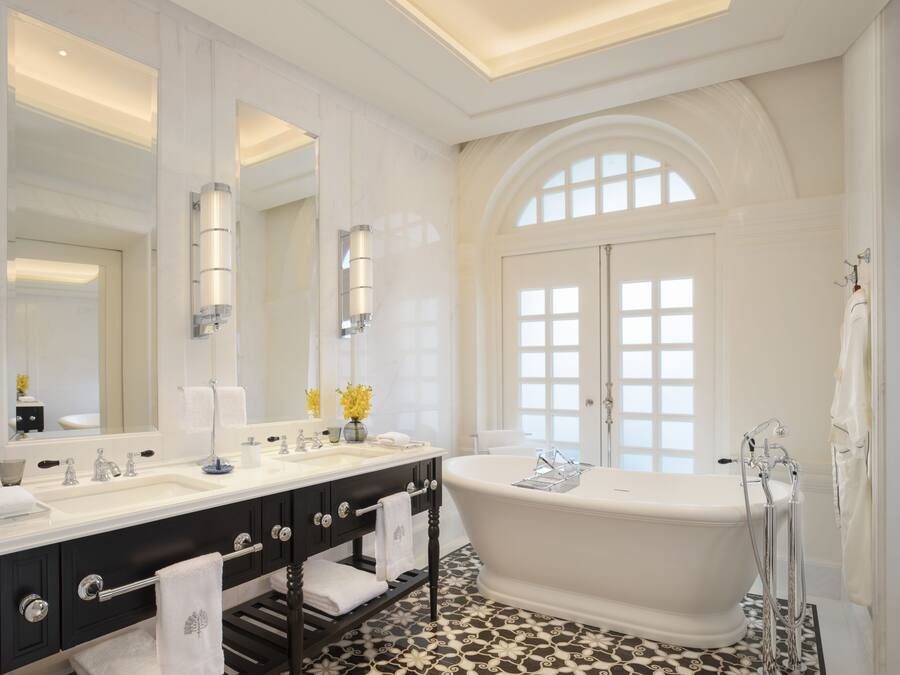 Un baño lujoso con una bañera independiente, un lavabo doble con un espejo grande y un suelo de baldosas estampadas.