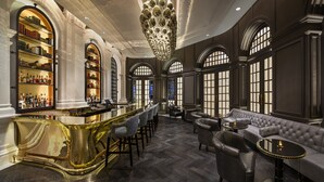 Un bar luxueux avec un comptoir doré, des chaises à haut dossier et un canapé moelleux.