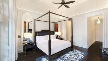 A four-poster canopy bed with a dark wooden frame and white bedding, flanked by nightstands with lamps and a vase.