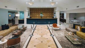 Eine großzügige Lobby mit einer Rezeption, einer Sitzecke und einer Zierpflanze.