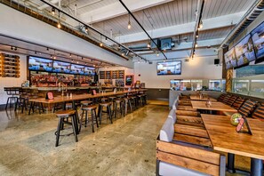 Enjoy social dining and entertainment at this modern bar area with a long counter, TVs, and a selection of beverages.