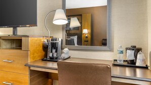 A hotel room with a wooden desk, a coffee maker, a lamp, a mirror, and a television. - Best Western Queens Gold Coast (Bayside)