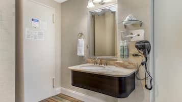 A bathroom with a double sink, a large mirror, a towel ring, and a hairdryer on the wall.