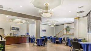 A spacious conference room with multiple tables and chairs, a reception area with a counter, and a staircase leading to another floor. - Best Western Queens Gold Coast (Bayside)