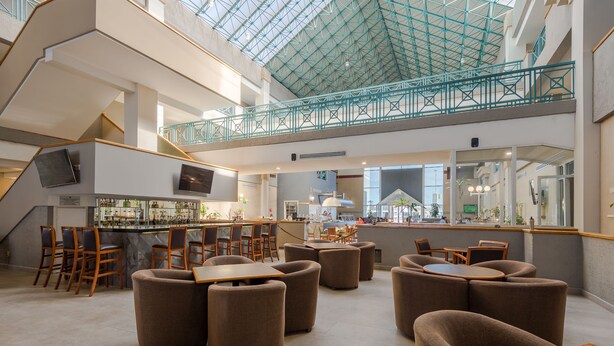 A spacious indoor area with a high ceiling and a glass roof, featuring seating areas and a bar. - Casa Grande Delicias (Delicias)