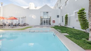 A modern building with a swimming pool, outdoor seating, and neatly trimmed hedges. - Casa Grande Delicias (Delicias)