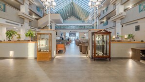 A spacious lobby with a high ceiling, glass panels, and a central staircase. - Casa Grande Delicias (Delicias)