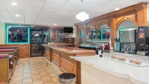 Un restaurant amb zona de bar, seients de fusta i una màquina de cafè.
