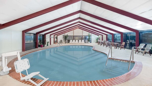 Una piscina interior amb vora de rajola, envoltada de gandules i taules.