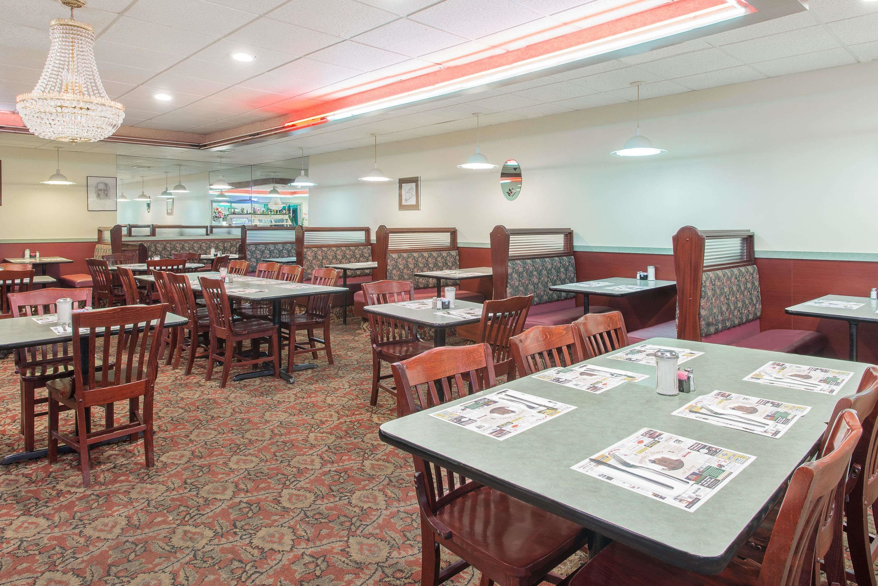 A restaurant with booths and tables, carpeted floors, and hanging lights.