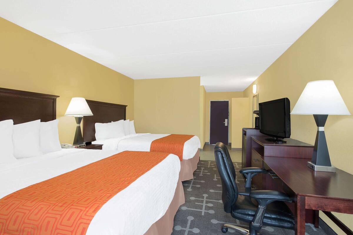 A hotel room with two beds, a desk with a computer, and a TV.