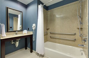A bathroom with a bathtub, a sink, a mirror, a shower, and a hand dryer.