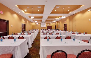 A conference room with multiple tables, chairs, and water bottles.