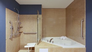 Ein Badezimmer mit Badewanne, Dusche und Handläufe.