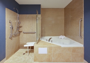 A bathroom with a bathtub, a shower, and a handrail.