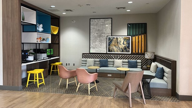 Ein stilvoller Lounge-Bereich mit einer Couch, Sesseln, einem Couchtisch und einem Bücherregal.