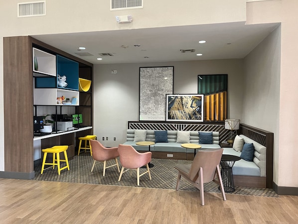 A modern lounge area with a sofa, chairs, a coffee table, and a bookshelf.