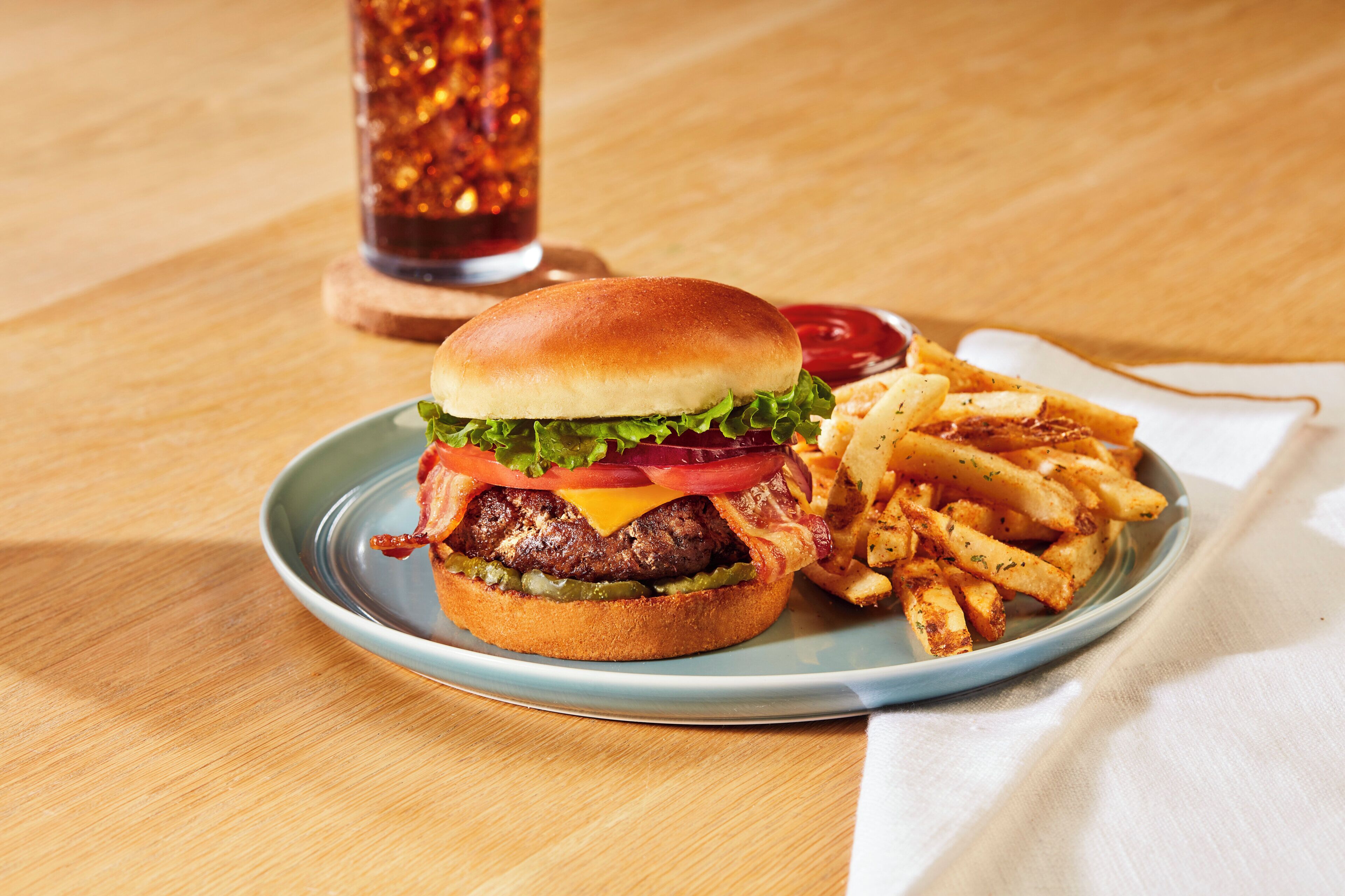 A plate with a burger and fries on a wooden table.