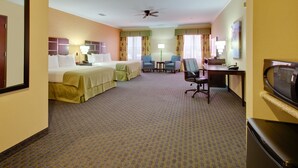 Ein Hotelzimmer mit zwei Betten, einem Schreibtisch, einem Stuhl, einem Fernseher und einem Deckenventilator.