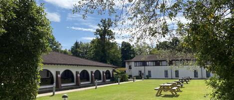 A courtyard with picnic tables, a building with arched windows, and a clear sky.
