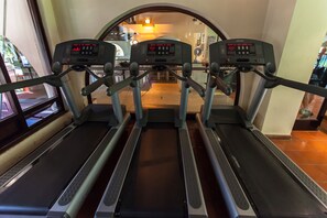 Three treadmills in a gym with a window view.