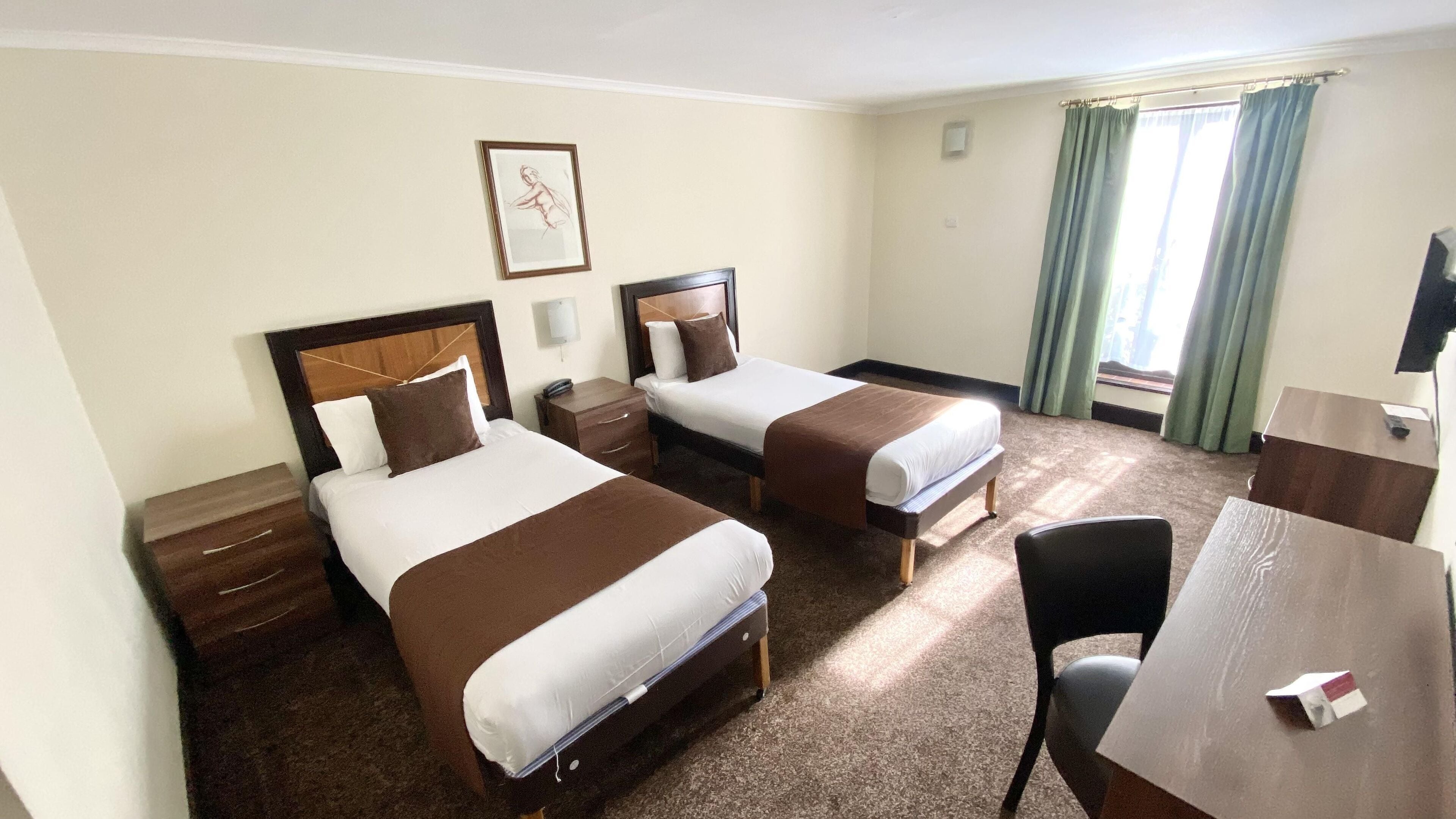 Habitación de hotel con dos camas, un escritorio, una silla, un televisor y un ventanal con cortinas.