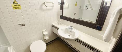 A small bathroom with a toilet, sink, and mirror. There is a caution sign on the wall and a towel hanging on the wall.