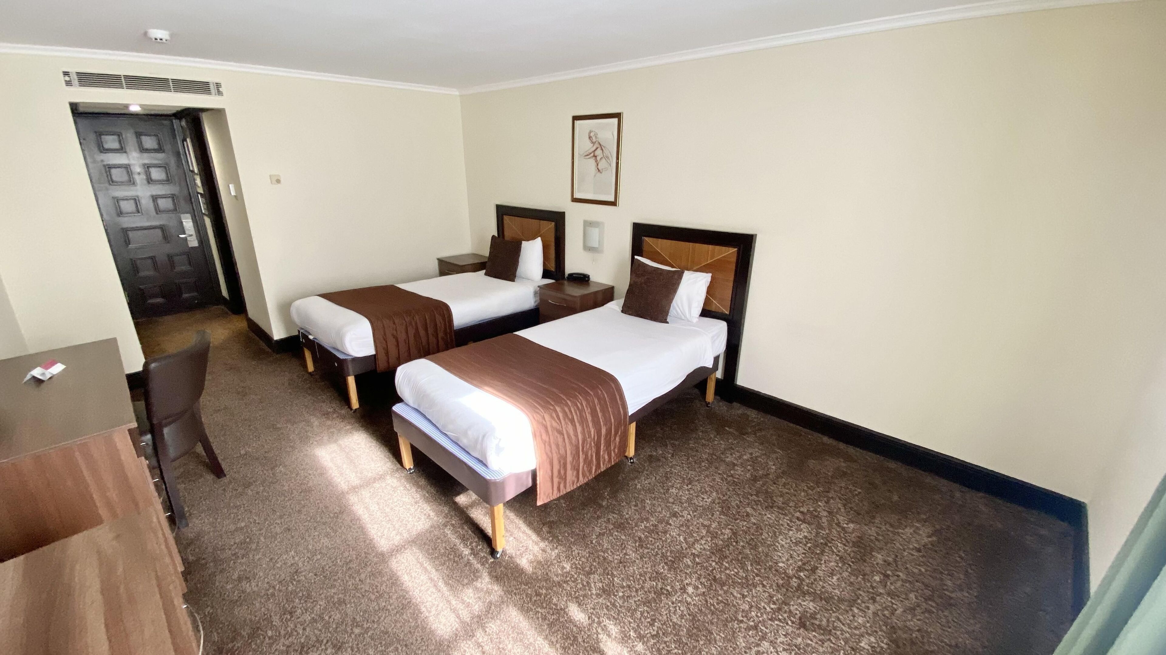 Een hotelkamer met twee bedden, een bureau en een stoel.