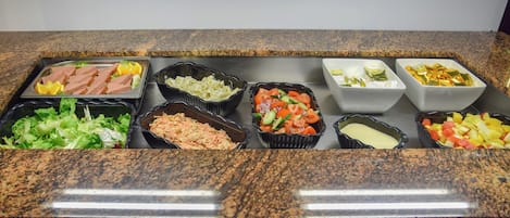 A buffet with various food items including salads, vegetables, and meats.