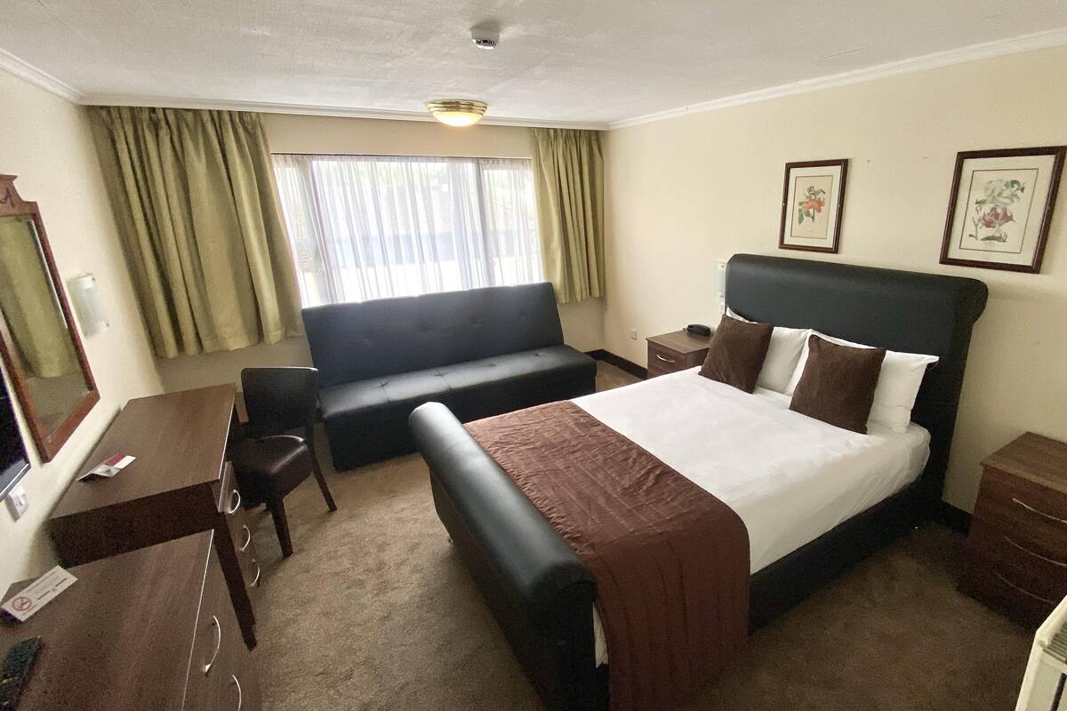 A hotel room with a bed, a sofa, a desk, and a chair.