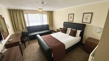 A hotel room with a bed, a sofa, a desk, and a chair.