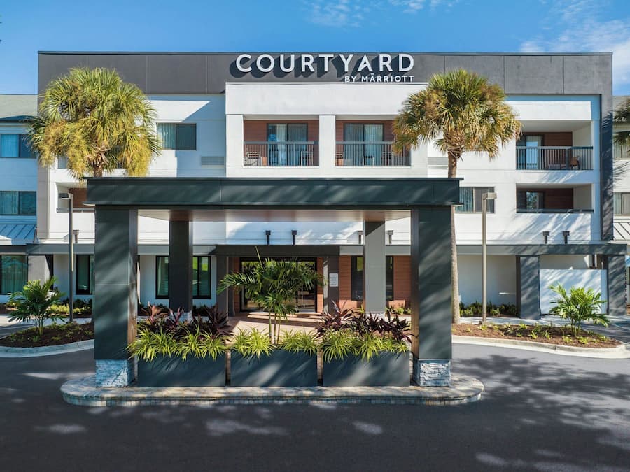 A Courtyard by Marriott hotel with a covered entrance, palm trees, and a modern building facade.