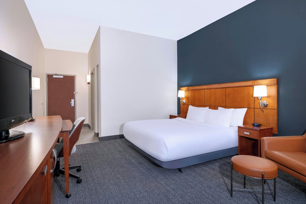 Une chambre d’hôtel équipée d’un lit, d’un bureau, d’une chaise, d’une télévision et d’une table de chevet avec une lampe.