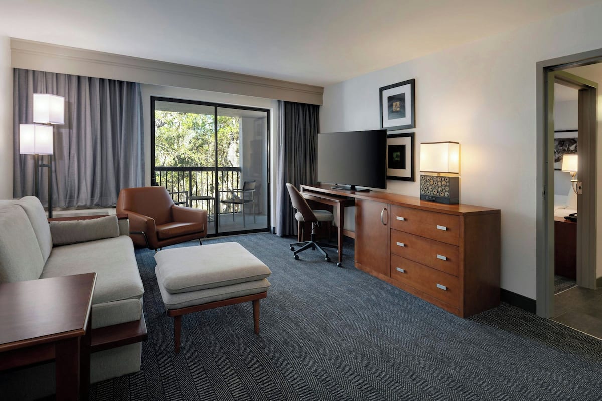 Une chambre d’hôtel équipée d’un canapé, d’un fauteuil, d’un bureau, d’une télévision et offrant une vue sur l’extérieur.