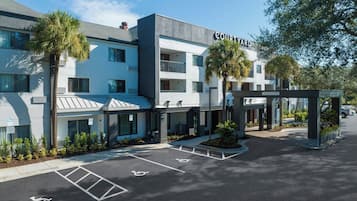Stylish hotel with modern design, flat roof, and balconies, surrounded by lush greenery and accessible parking.