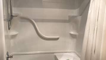 A walk-in shower with a glass door, a handheld showerhead, a towel rack, and a toilet.