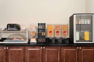 Una barra de desayuno con un tostador, tazones y recipientes de cereal y leche.