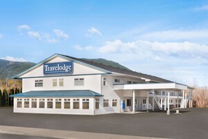 Edificio Travelodge con un espacio exterior cubierto y una montaña al fondo.