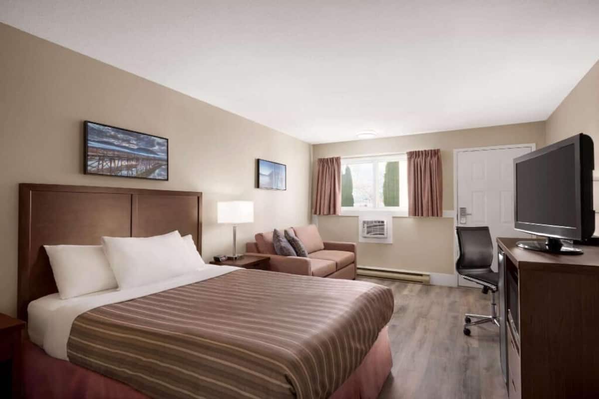 Une chambre d’hôtel avec un grand lit, un bureau avec un ordinateur, une chaise, un canapé et un téléviseur.