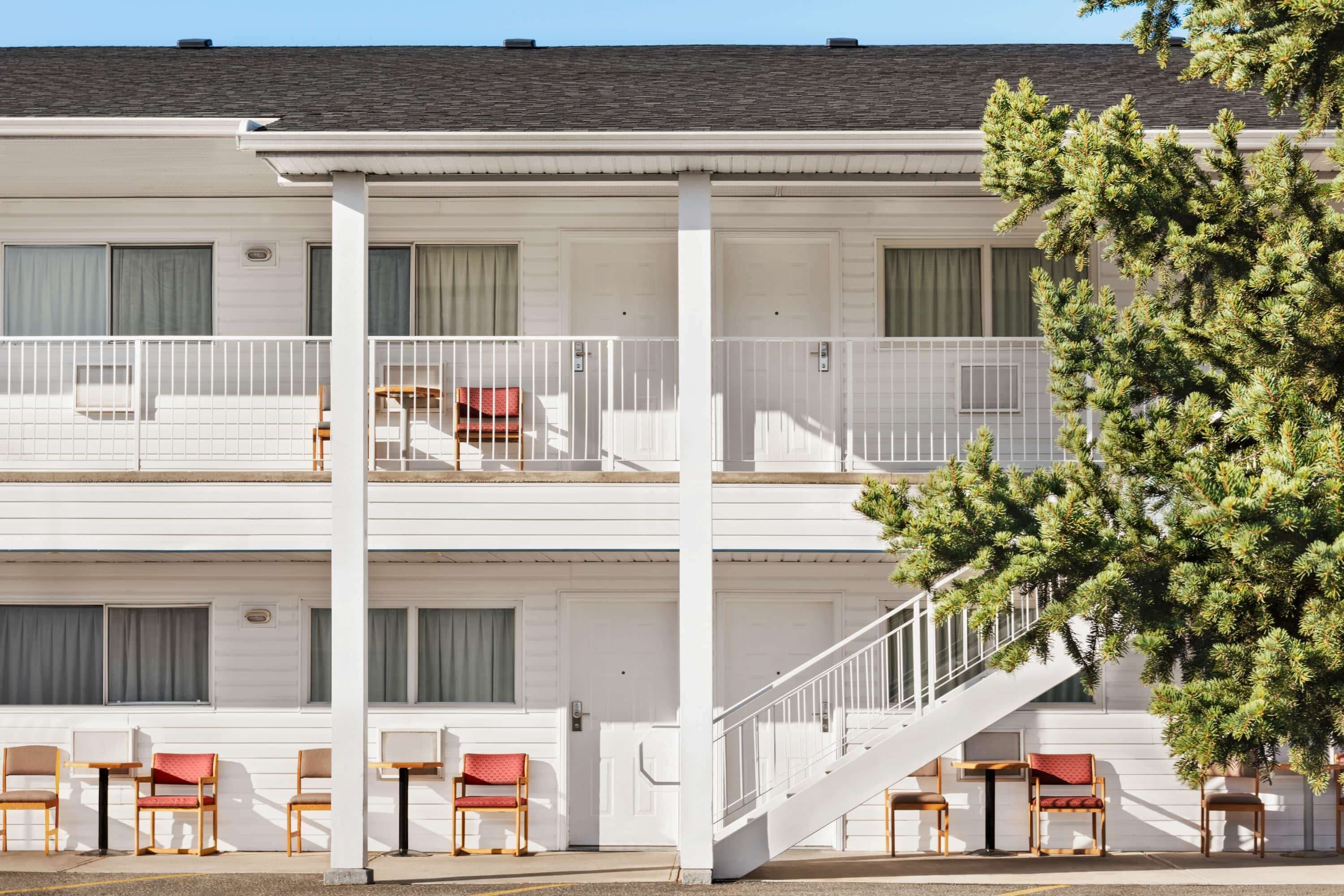 A two-story motel with a white exterior, a balcony on the upper floor, and a staircase leading to the upper level.