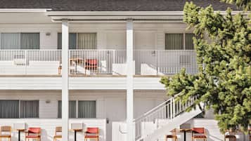 A two-story motel with a white exterior, a balcony on the upper floor, and a staircase leading to the upper level.