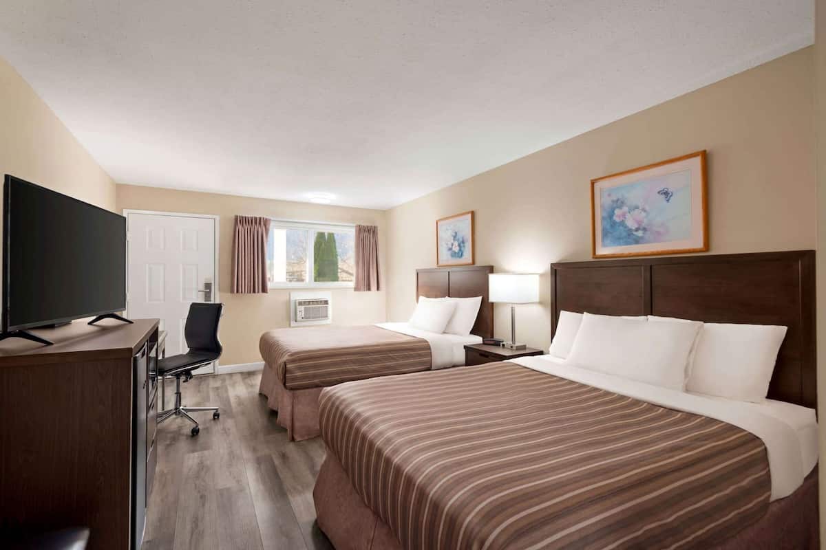 Une chambre d’hôtel avec deux lits, un bureau, une télévision et une chaise.