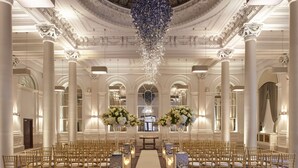 A grand hall with a central aisle, ornate columns, and chandeliers.