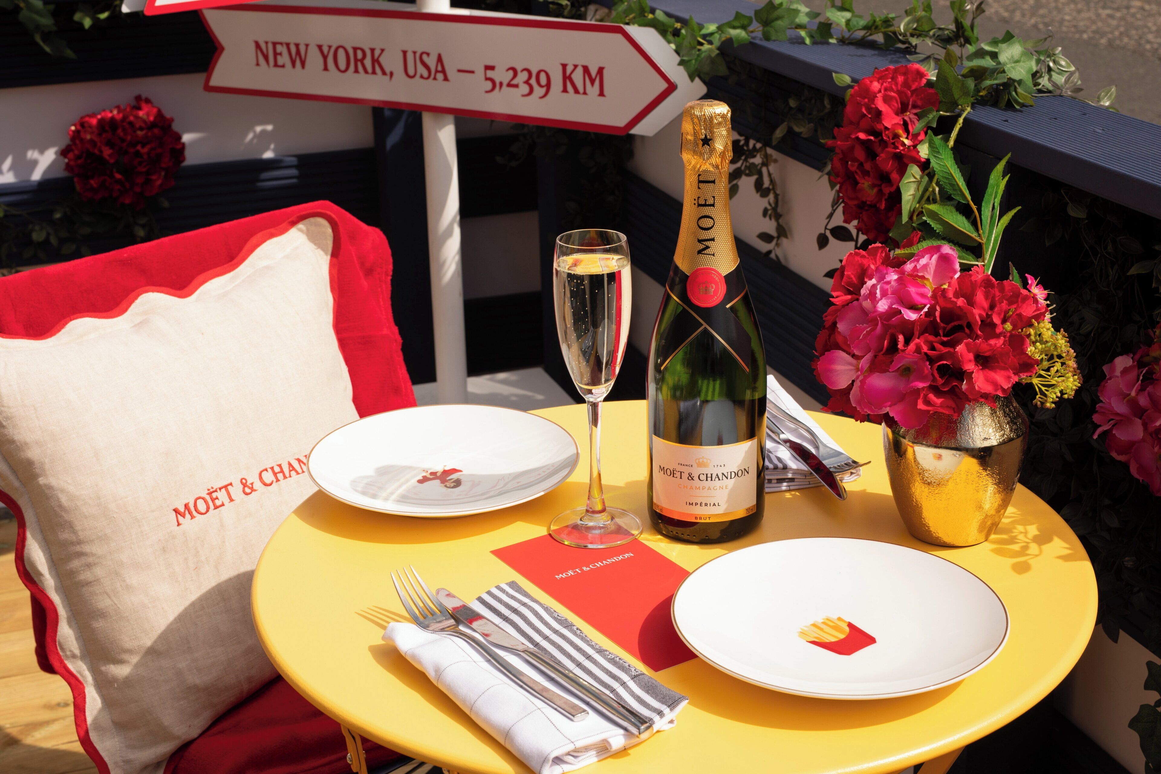 A table set with plates, a bottle of champagne, cutlery, and a napkin.