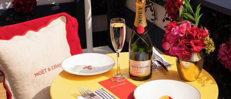 A table set with plates, a bottle of champagne, cutlery, and a napkin.
