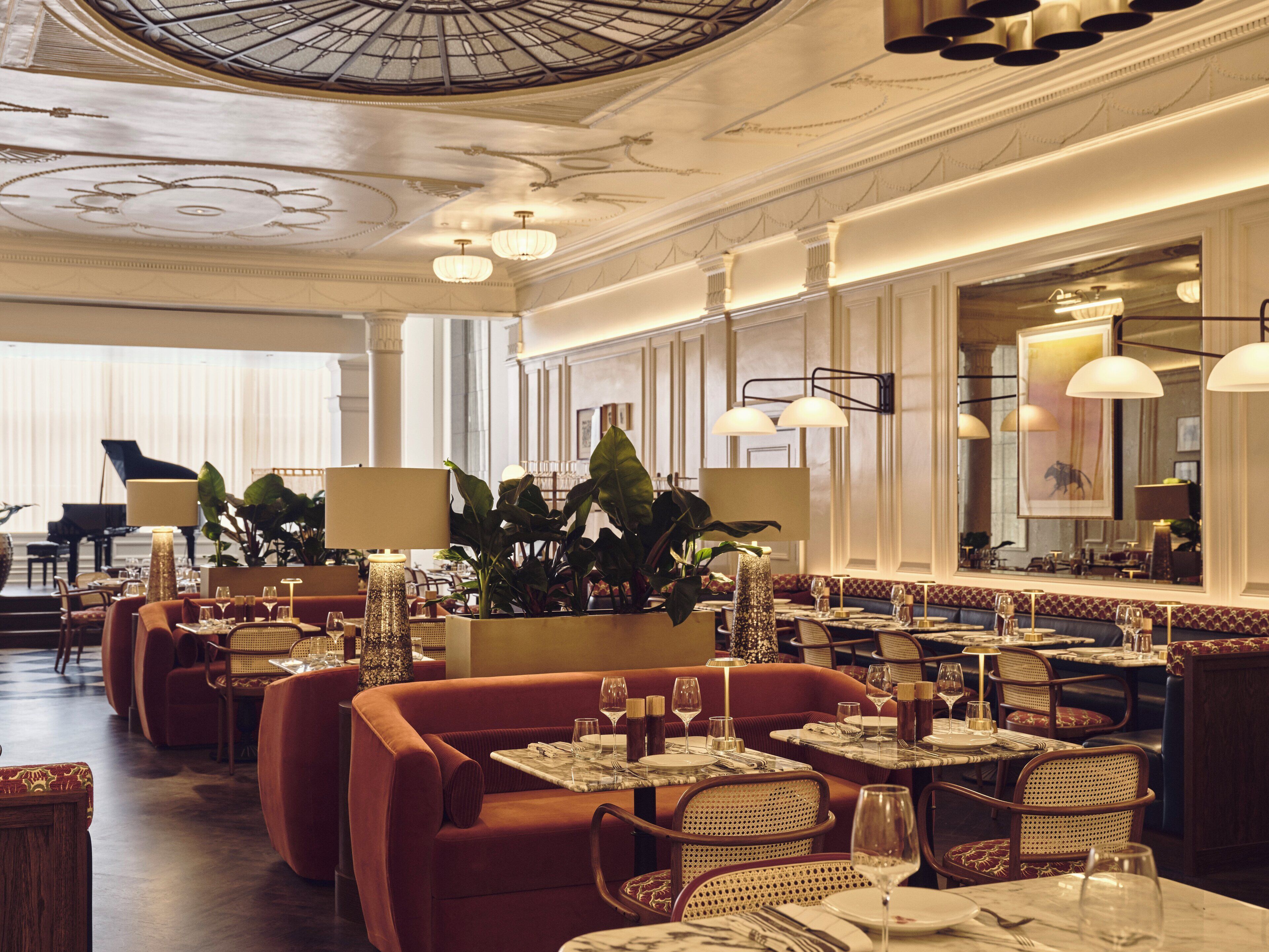 Un restaurant au décor classique, avec un piano à queue, des fauteuils confortables et une décoration de table élégante.