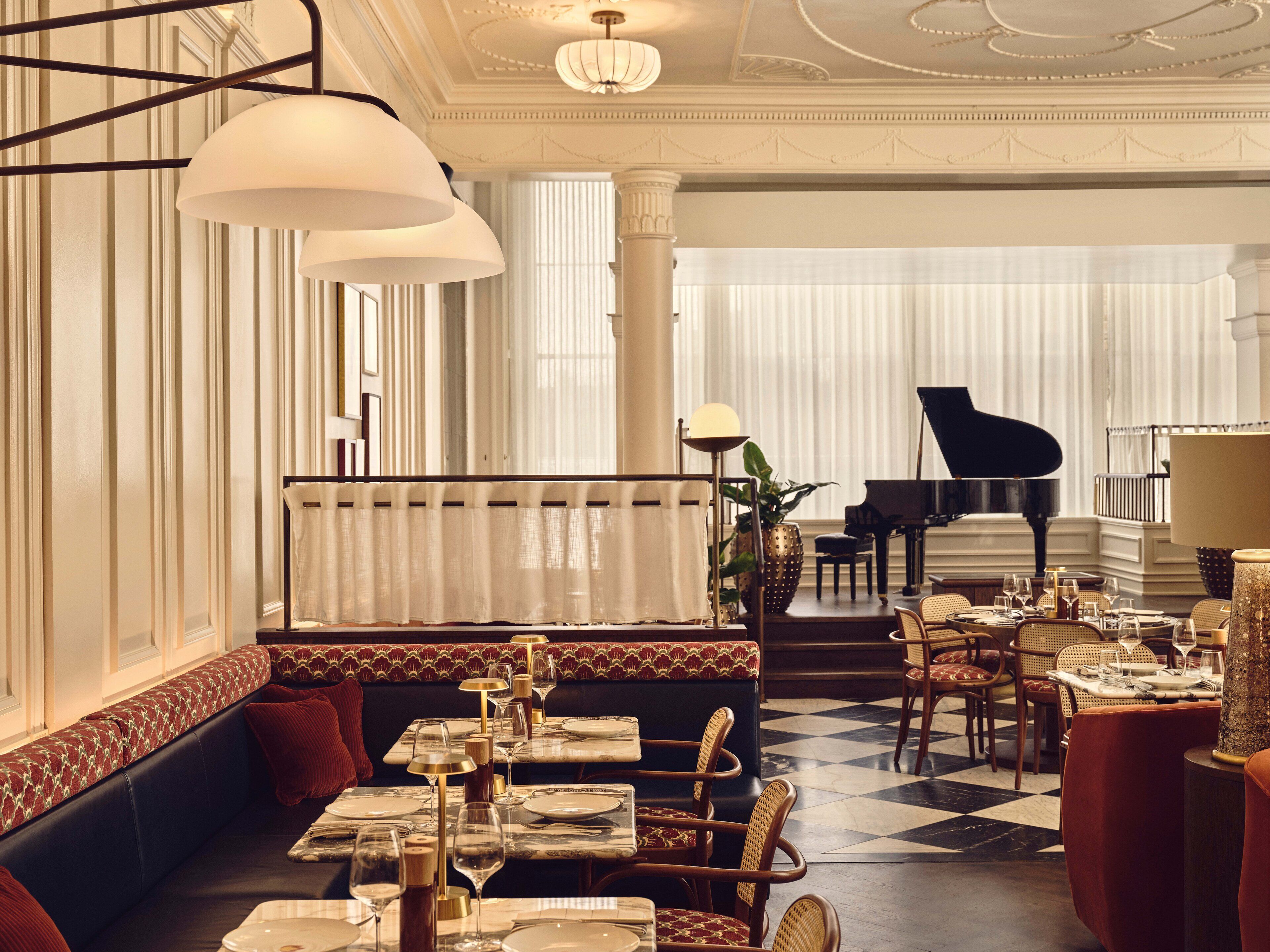 Un'elegante sala da pranzo con pianoforte, arredi raffinati e pavimento a scacchi.