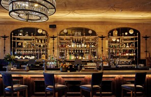 A bar with multiple shelves of bottles and glasses, a cash register, and bar stools. - InterContinental Edinburgh The George by IHG (Edinburgh)