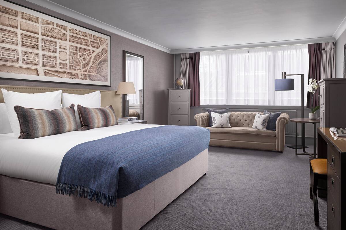 Et hotelværelse med en stor seng, en sofa, et skrivebord og et kort på væggen.