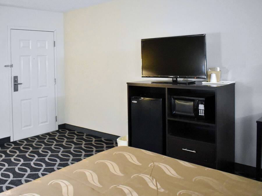 Een hotelkamer met een bed, een televisie, een magnetron en een klein kastje.